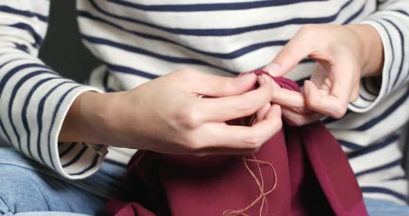 Sews with a needle and thread by hand