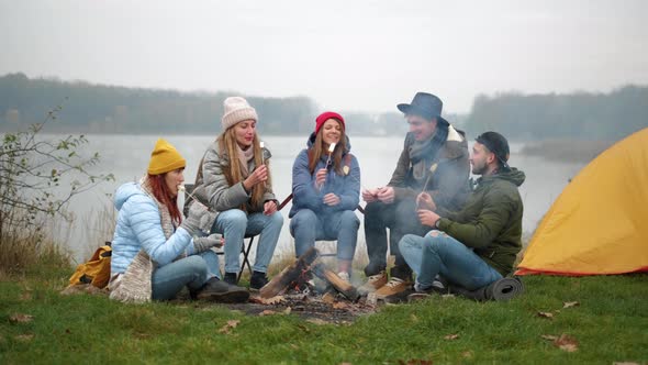 Hungry Travelers Are Cooking Marshmallow on Fire and Eating It From Sticks During Conversation