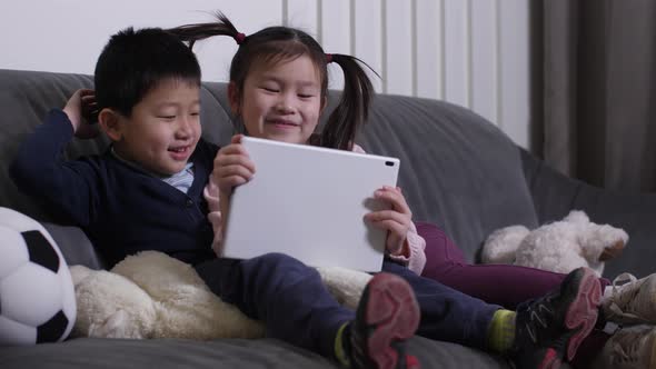 Smiling Asian Kids Watching Funny Video on Tablet