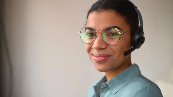 Headshot of Smiling Young Female Employee Wearing Wireless Headset Looking at Camera