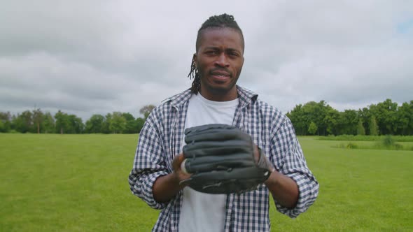 Portrait of Handsome Black Man in Baseball Glove Throwing Ball Outdoors