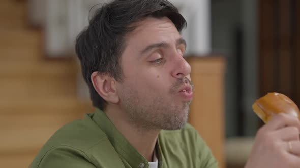 Closeup Portrait of Handsome Caucasian Young Man Enjoying Taste of Delicious Homemade Freshlybaked