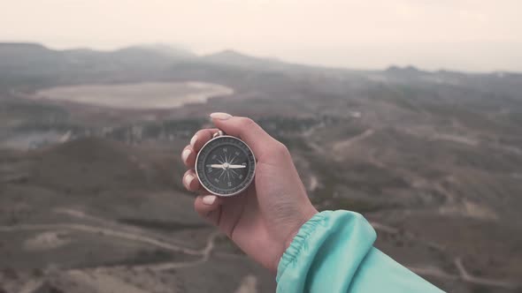 Woman Hand with a Compass in Front of Mountain Valley