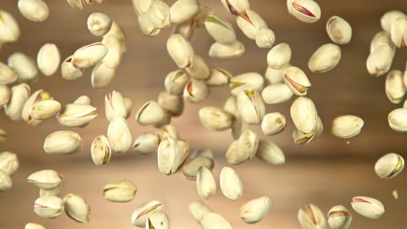 Super Slow Motion Shot of Falling Pistachios After Being Exploded on Wooden Background at 1000Fps
