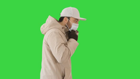 Winter-like Dressed Caucasian Man Putting on Medical Mask on a Green Screen, Chroma Key