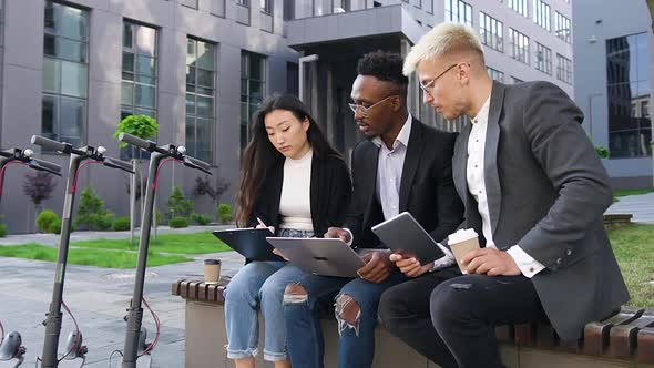 Mixed Race Office Coworkers which Talking Outdoors During Working Under Joint Computer Project