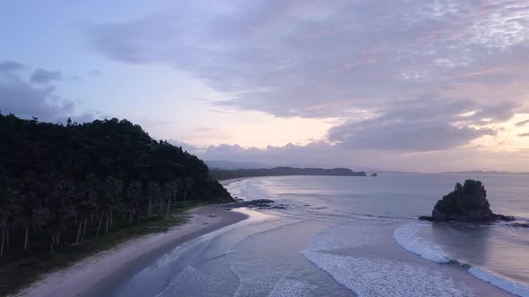 Aerial lateral tracking shot from beach coastline to open ocean at sunset on Palawan, the Philippine