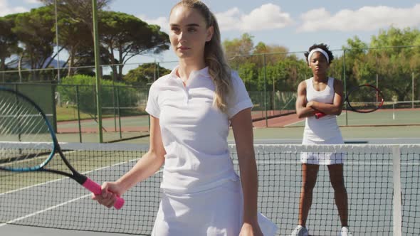 Video of diverse female tennis players standing on court and holding rackets