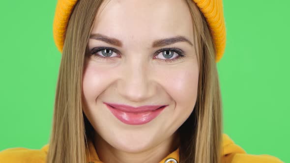 Woman in a Yellow Hat Looking Straight and Smiling. Close Up. Green Screen