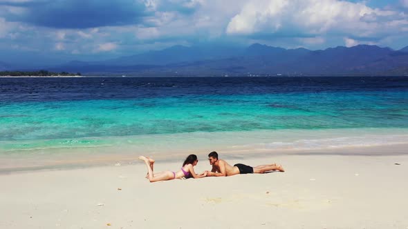 Man and lady in love on exotic coastline beach holiday by blue sea with bright sandy background of G