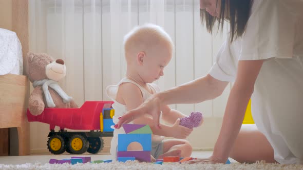 Mother and Her Kid Play with Toys Indoors. Crawling Funny Baby Boy on Floor at Home. Mother and