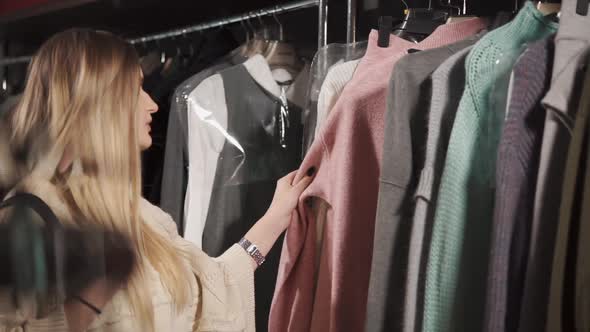 Pretty Girl Is Going Shopping To Clothes in Mall, Touching Goods on Racks