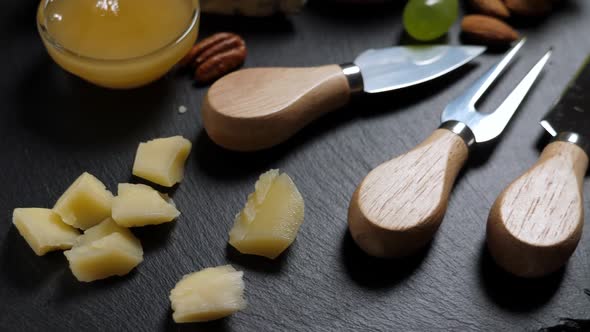 Sliced Cheese, Nuts, Grape, Honey and Knife on Shale Platter