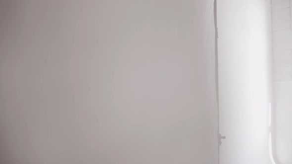 A Beautiful Young Girl in a Stretching Studio Moves Smoothly and Looks Out From Behind White Tulle