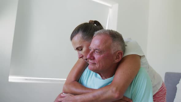 Caucasian senior woman hugging her husband from behind at home