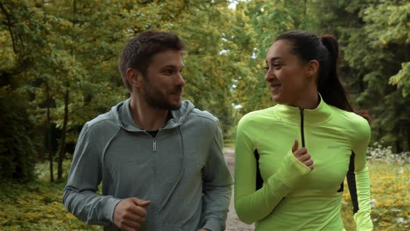 Young Male and Feemale Communicating and Smiling During Morning Jog. They Running at the Park