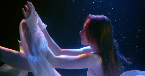 Magical Shot of Young Pretty Woman Moving Underwater in Slow Motion in Darkness