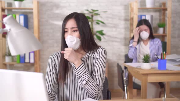 Two Sick Young Asian Office Workers in Protective Medical Masks on Their Faces