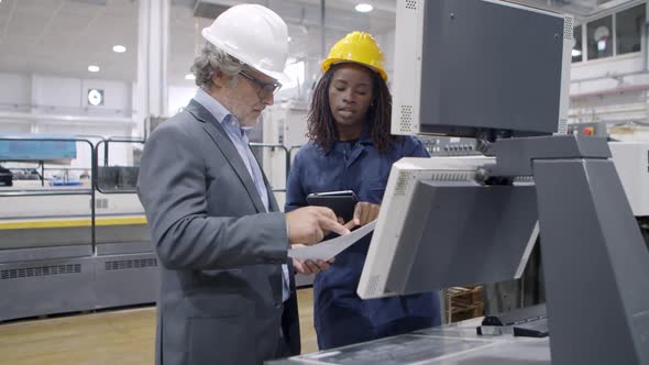 Black Female Factory Professional Standing at Control Panel