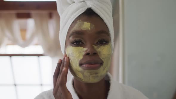 Portrait of african american attractive woman applying face mask in bathroom