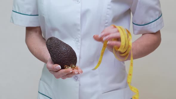 Nutritionist Doctor Healthy Lifestyle Concept - Holding Organic Avocado Fruit and Measuring Tape