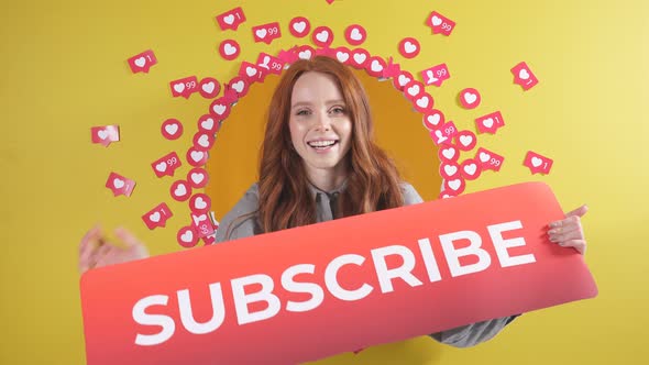 Portrait of a Redhaired Woman with a Smile Holds a Sign to Subscribe She Asks you to Subscribe and