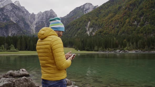 Hiker making video with smartphone at Fusine lake, Italy