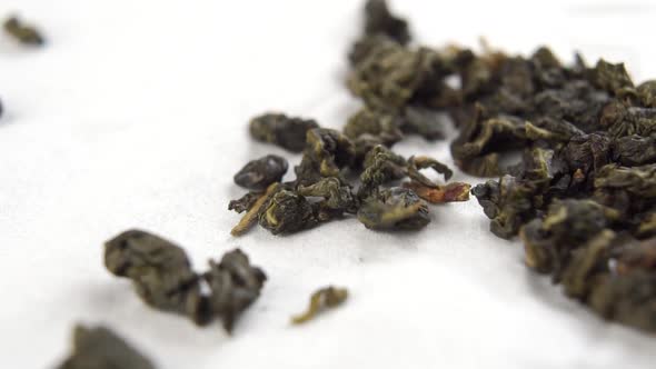 Pearls of green dried fermented Chinese oolong tea fall on a white paper napkin