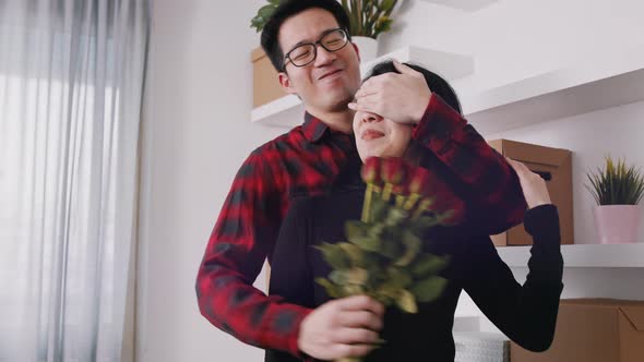 Young Man Closing Eyes of His Girlfriend with Hand and Gifting Her with Bouquet of Red Roses 