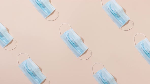 Pattern of Blue Medical Masks on a Pastel Pink Background Slow Motion