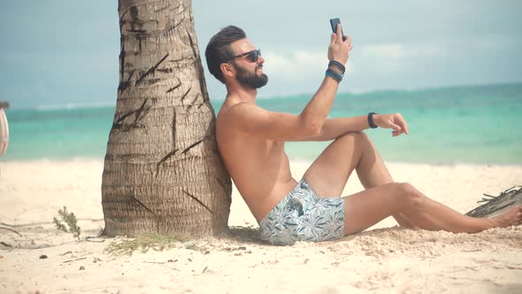 Businessman Working On Vacation.Man Sitting On Palm And Talking On Smartphone On Vacation Lounge Sea