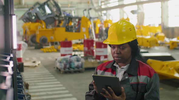 Female Quality Control Inspector Working on Tablet in Factory