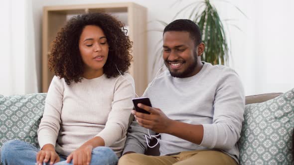 Happy Couple with Smartphone and Earphones at Home