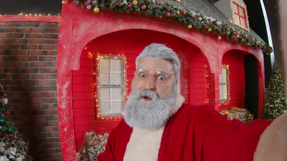 Portrait of Santa Claus Showing Rocker Hand Gesture and Filming Himself on Camera