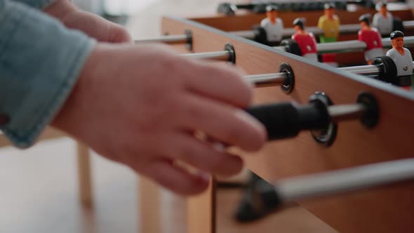 Close Up of Man Playing Soccer Game at Foosball Table