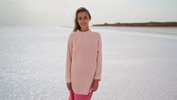 Hand Held Camera Shooting Beautiful Woman in Kozy Sweater and Pink Dress Walking at Windy Salty