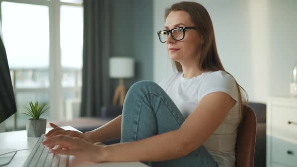 Casually Dressed Woman Working with a Computer at Home in a Cozy Environment