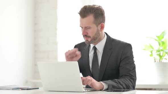 Young Businessman Coughing While Using Laptop in Office