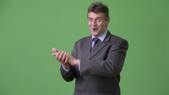 Mature Handsome Businessman Against Green Background