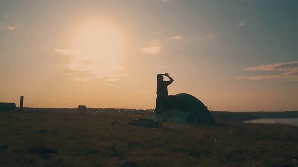 Silhouette of Man Going Out of Tent at Campsite on Hill