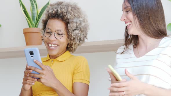 Two r Lesbian Girlfriends Looking at the Mobile and Smiling in an Apartment