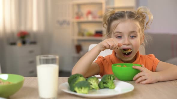 Cute Daughter Eating Breakfast Cereal With Milk, Mother Stroking Girl Head