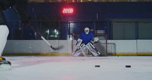 Close-up of a Hockey Puck in Slow Motion and a Putter of Several Pucks in Turn and a Goalkeeper in