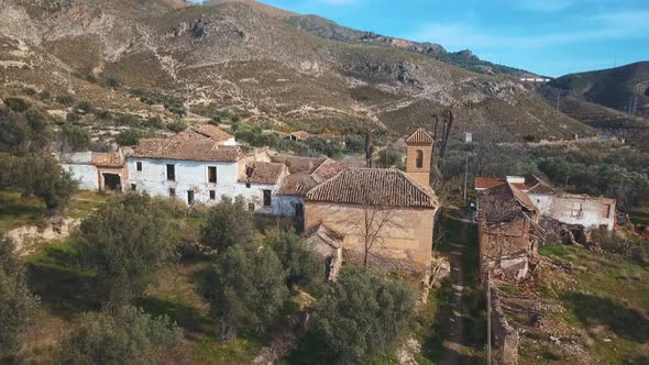 Aerial view of an abandoned village with a church surrounded by nature in Spain.