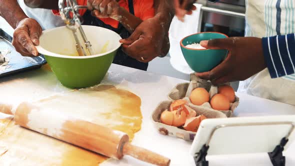 Boy learning to whisk eggs while preparing cookies