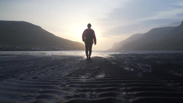 Man Walking Along Lake At Low Tide At Sunrise