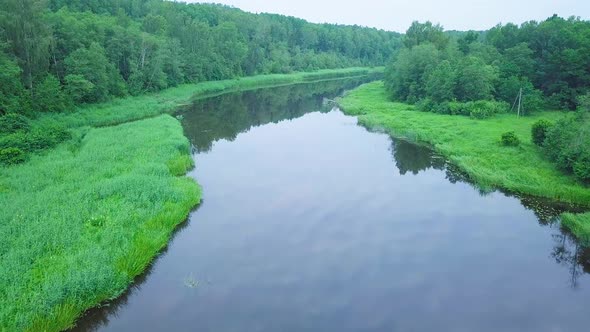 Aerial view of a Venta river (Latvia) on a sunny summer day, lush green trees and meadows, beautiful