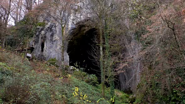 Flying Above a Monumental Cave Entrance Among Trees by Drone