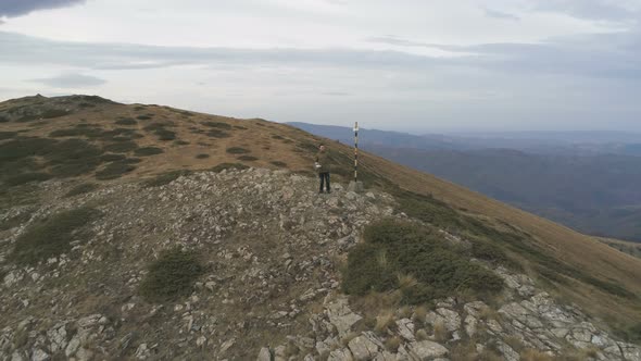 Young Man with Green Jacket Actively Resting During Trip Enjoying Freedom at Hill Top.