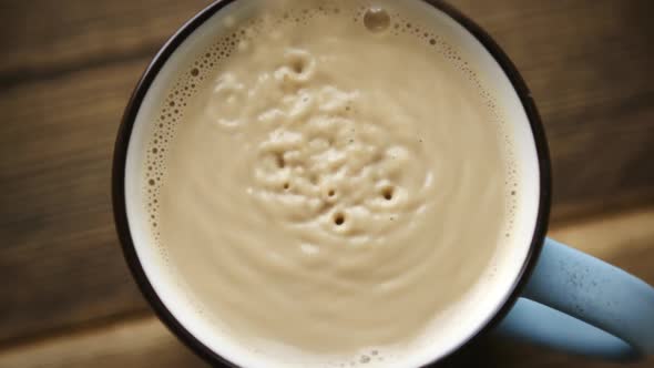 Pour Cane Sugar From Spoon Into Cup of Coffee with Milk